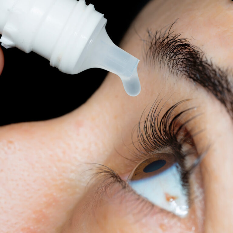 A close-up image of an eyedrop bottle above an open eye