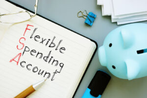 Ledger with Flexible Spending Account written on it, along with a piggybank