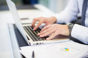 worker on a laptop with printed graphs